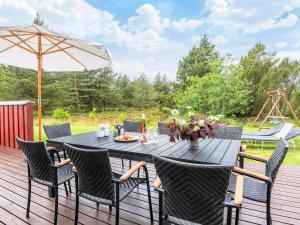 a table and chairs on a deck with an umbrella at 4 star holiday home in Rømø in Kongsmark