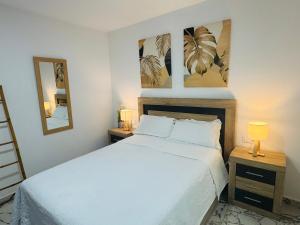 a bedroom with a white bed and two night stands at Aladín House Vinaròs playa in Vinarós