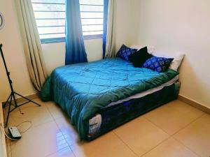 Un dormitorio con una cama con sábanas azules y una ventana. en Madalitso Guest House, en Lusaka