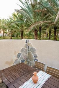 a table with a vase sitting on top of a patio at Under The Tree in Al Ḩamrāʼ