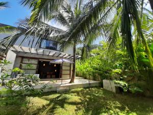 a small building with an umbrella in a garden at El Nido Villa Rentals in El Nido