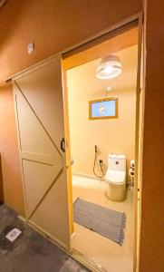 a bathroom with a toilet and a sliding door at Under The Tree in Al Ḩamrāʼ +62 photos