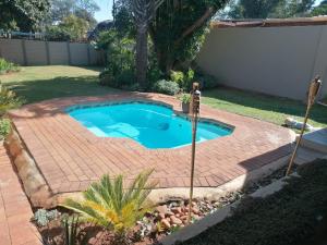 a small swimming pool in a yard with a brick patio at F'leur Guesthouse in Mokopane