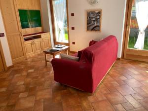 a living room with a red chair and a table at Appartamento 'Reit' - Bormio - giardino, parcheggio, Wi-fi in Bormio