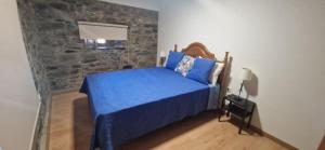a bedroom with a blue bed with a stone wall at Your Idyllic Countryside Getaway in Sertã