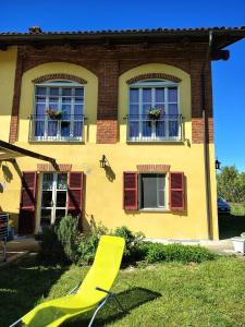 a yellow house with two windows and a yellow chair at BED & BREAKFAST AL BRICCO in Cantarana