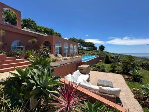 a house with a swimming pool next to a resort at Villa Anna Splendid Sunset Ocean Front in Mosteiros