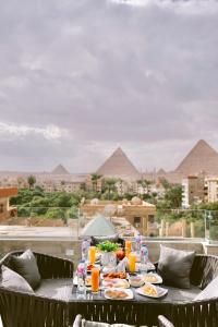 a table with food and drinks on a balcony with pyramids at pyramids stone&tuya&view in Cairo