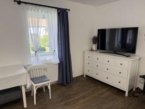 a bedroom with a tv and a dresser with a window at Hűvösvölgy Vendégház in Lókút