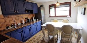 une cuisine avec des placards bleus et une table et des chaises blanches dans l'établissement Top Komfort Apartment, 3 Zimmer inkl privater Küche und Bad WC, Erdgeschoss, inkl Frühstück und Getränke, Free WiFi, Parkplatz, Smart TV, Top Lage in Kassel, so Privat wie zu Hause, à Cassel