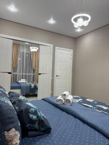 ein Schlafzimmer mit zwei Betten mit blauer Bettwäsche und einem Spiegel in der Unterkunft 4YOU Shymkent евро2 in Schymkent
