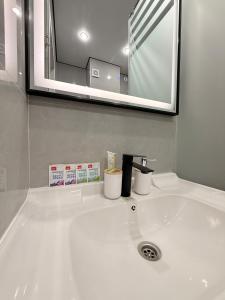 ein weißes Waschbecken mit zwei Tassen und einem Spiegel in der Unterkunft 4YOU Shymkent евро2 in Schymkent