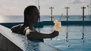 a woman holding a drink in a swimming pool at Arrival Beach and Spa in Gulhi