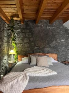 a bed in a room with a stone wall at Vigia dos Machados in Lajes do Pico