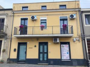a yellow building with flowers on a balcony at Ame Casa - Accoglienza Diffusa in Licodia Eubea
