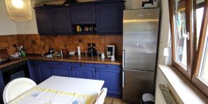 a kitchen with blue cabinets and a stainless steel refrigerator at 4 Zimmer Ferienwohnung mit privater Küche, Bad und WC, mit Gratis Frühstück, Parkplätze und WiFi in Kassel