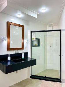 a bathroom with a sink and a glass shower at Pousada Vieira in Arraial do Cabo