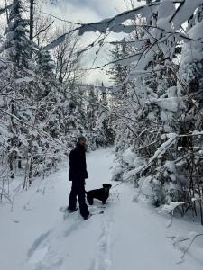 a man and a dog in the snow at Chalet Beausite in Saint-Philémon