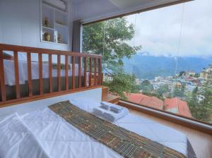 una camera da letto con un letto e una grande finestra di Sapa Succulent Garden Homestay - Vườn Sen Đá Homestay a Sa Pa