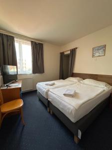 a hotel room with two beds and a desk at Corvin Hotel in Győr