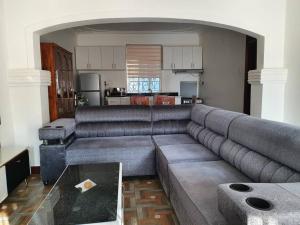 a living room with a large couch and a kitchen at UZIMA HOMEs in Fort Portal