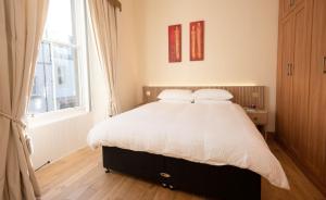 a bedroom with a bed with white sheets and a window at Coastal Escape 3 Bed Apartment Near the Beach in North Berwick
