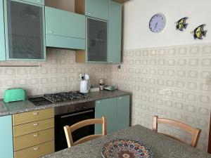 a kitchen with blue cabinets and a table with a clock on the wall at Residence Pineta in Loiano