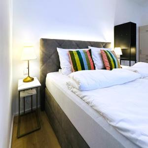 a bed with white pillows and a side table with a lamp at Villa Romana Apartments with Terrace & Private Entrance in Baden