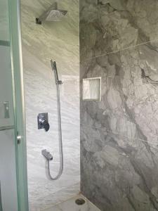 a shower in a bathroom with a stone wall at Utsava Homestay in Chitradurga