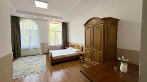 a bedroom with a bed and a large wooden cabinet at Promenade Park Hotel in Shymkent