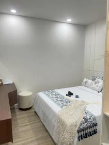 ein Schlafzimmer mit einem Bett und einer weißen Wand in der Unterkunft The Lumiere Riverside Apartment View City in Ho-Chi-Minh-Stadt