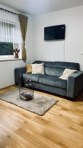 a living room with a blue couch and a wooden floor at Donovaly Apartman Galileo in Donovaly