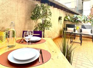 un tavolo di legno con sopra piatti e bicchieri da vino di L'Écrin d'Or - Élégant & Confortable- Idéalement Situé en Centre-Ville - Terrasse - Gare à 5 min a Valence
