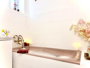 una vasca da bagno in un bagno bianco con fiori di L'Écrin d'Or - Élégant & Confortable- Idéalement Situé en Centre-Ville - Terrasse - Gare à 5 min a Valence