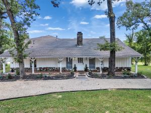 una casa blanca con árboles delante en Pool, Spa&Lake 16 beds 8 bathrooms 50 car parking VENUE Magnolia Texas, en Magnolia