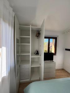1 dormitorio con estantes blancos, 1 cama y ventana en Attico zona mare, en Cattolica