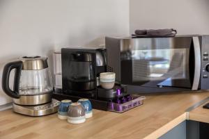 a kitchen counter with a coffee maker and a microwave at Escapade urbaine CDG Paris a deux pas in Le Blanc-Mesnil