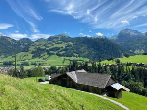 ein Haus auf einem Hügel mit Bergen im Hintergrund in der Unterkunft Ferienhaus Schönenmatte in Zweisimmen + 1 Foto