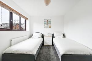 two beds in a room with two windows at Quiet & Modern Contemporary Home for Work & Family in Bedford