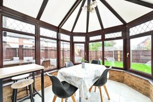 a conservatory with a table and chairs and windows at Quiet & Modern Contemporary Home for Work & Family in Bedford