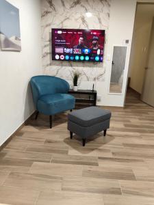 ein Wohnzimmer mit einem blauen Stuhl und einem TV in der Unterkunft Departamento en Centro Histórico, Ciudad de Mexico in Mexiko-Stadt + 3 Fotos