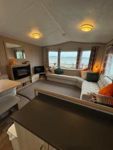 a living room with a couch and a table at Stunning Clearwater Lake View Caravan in Crowle