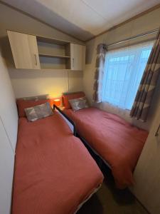 two beds in a small room with a window at Stunning Clearwater Lake View Caravan in Crowle
