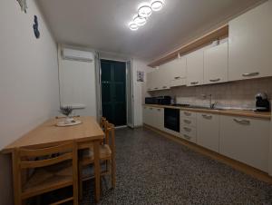 une cuisine avec des armoires blanches et une table en bois dans l'établissement La Casa Al Mare, à Vado Ligure