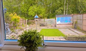 ein Blick auf einen Garten aus einem Fenster mit einer Pflanze in der Unterkunft Modern luxury 3-bedroom guesthouse in Wigan in Wigan