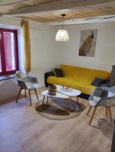 a living room with a yellow couch and chairs at Appartement cozy maison Ed Den in Tauves