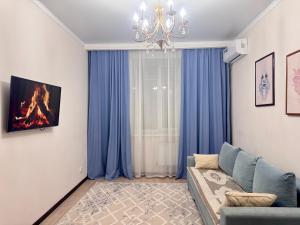 ein Wohnzimmer mit blauen Vorhängen und einem Sofa in der Unterkunft Апартаменты в ЖК Ирина рядом с Баянтау in Pawlodar