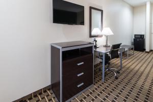 um quarto de hotel com uma secretária e uma televisão na parede em Scottish Inns & Suites em Balch Springs