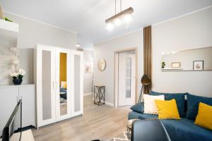 a living room with a blue couch and yellow pillows at Cozy Warsaw Apart with Gym close to the Airport and City Centre in Warsaw