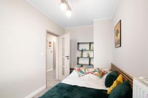 a bedroom with white walls and a bed with green pillows at Cozy Warsaw Apart with Gym close to the Airport and City Centre in Warsaw